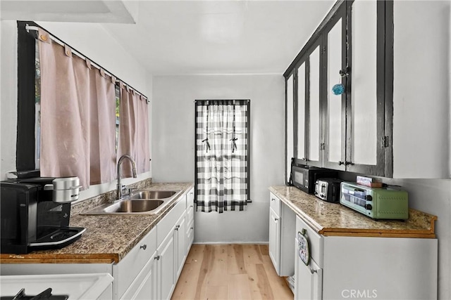 kitchen with sink, light hardwood / wood-style flooring, and white cabinetry