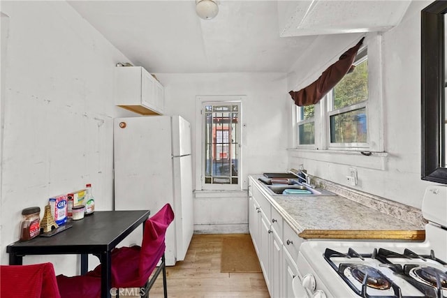 kitchen with sink, white cabinets, light hardwood / wood-style floors, and white appliances