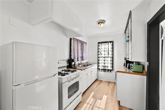 kitchen with white appliances, white cabinets, light hardwood / wood-style floors, and sink