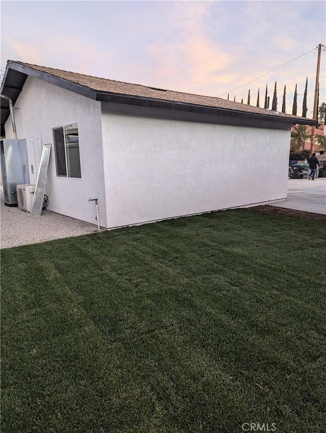 property exterior at dusk with a lawn and ac unit