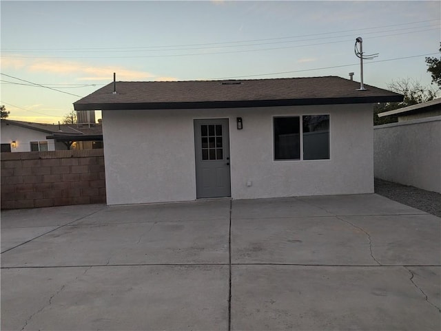 back house at dusk featuring a patio area