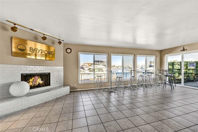 living room featuring a water view, a brick fireplace, and tile patterned floors