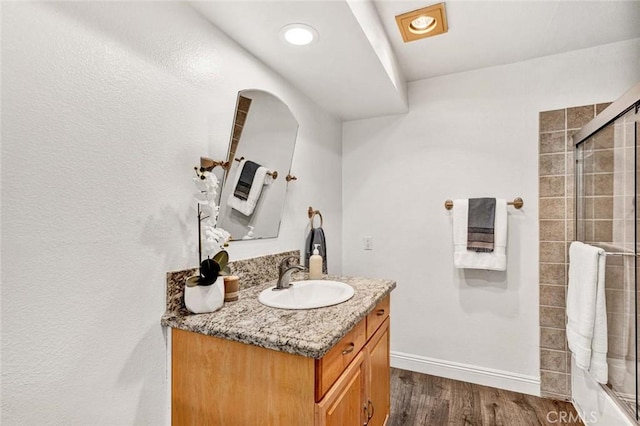 bathroom with a shower with door, hardwood / wood-style floors, and vanity