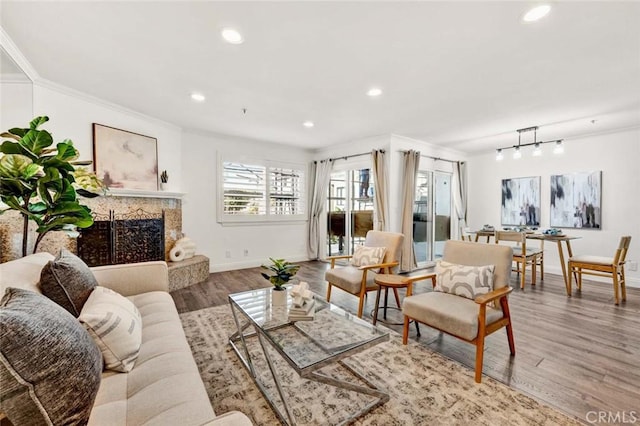 living room featuring wood-type flooring, a high end fireplace, and crown molding