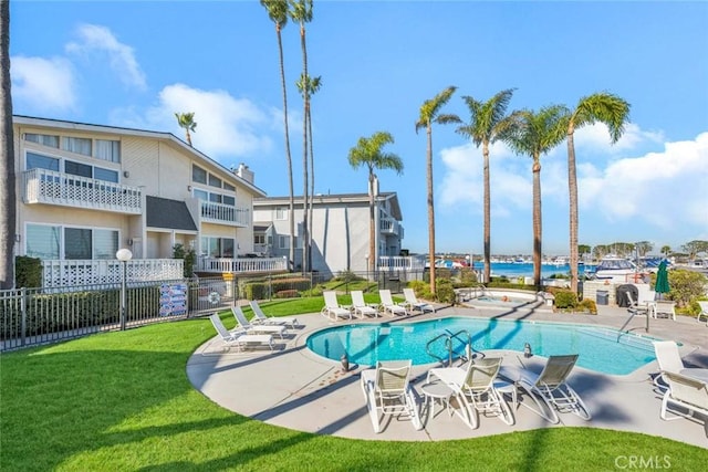 view of pool featuring a patio area, a water view, and a yard