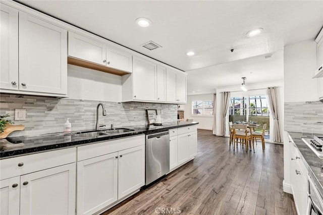 kitchen featuring white cabinetry, dark stone countertops, wood-type flooring, stainless steel dishwasher, and sink