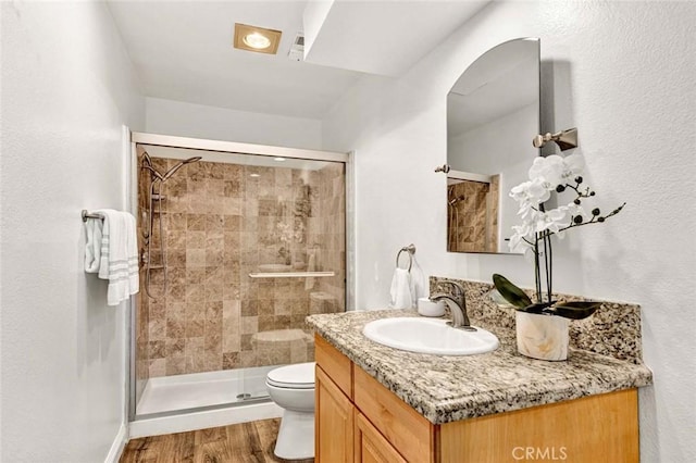 bathroom with toilet, a shower with door, hardwood / wood-style flooring, and vanity