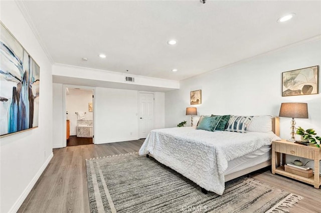 bedroom featuring ensuite bathroom, ornamental molding, and hardwood / wood-style floors