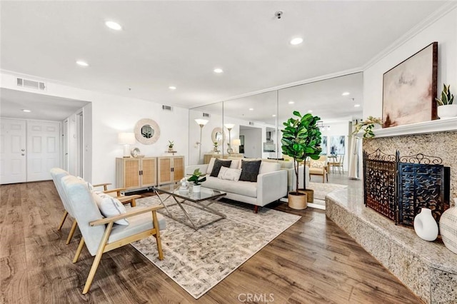 living room featuring hardwood / wood-style flooring, a high end fireplace, and crown molding