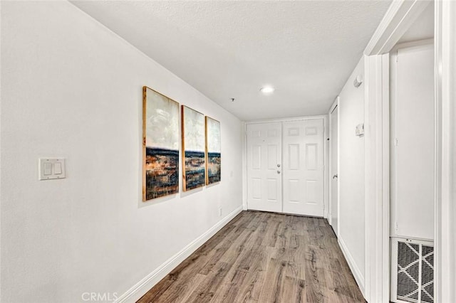 hallway with a textured ceiling and wood-type flooring