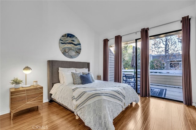 bedroom featuring hardwood / wood-style flooring, lofted ceiling, and access to outside