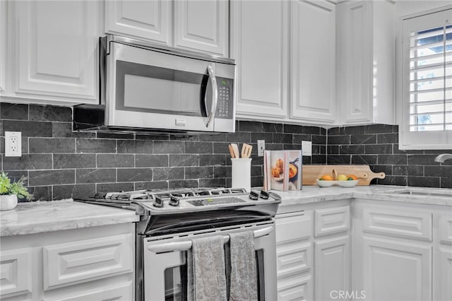 kitchen featuring stainless steel appliances, sink, white cabinets, and backsplash