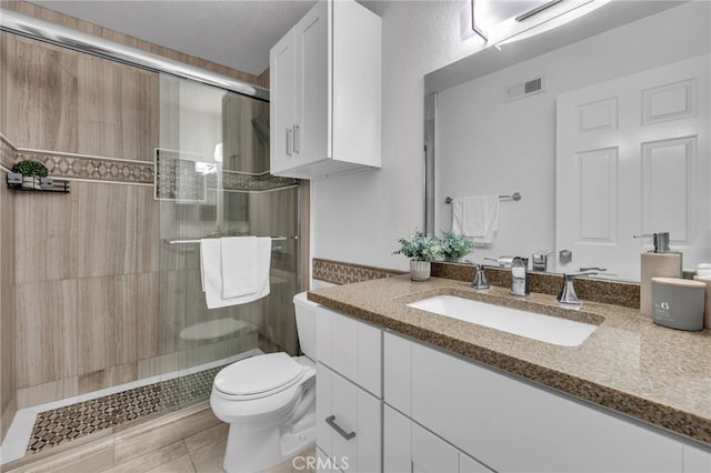 bathroom featuring vanity, an enclosed shower, tile patterned floors, and toilet