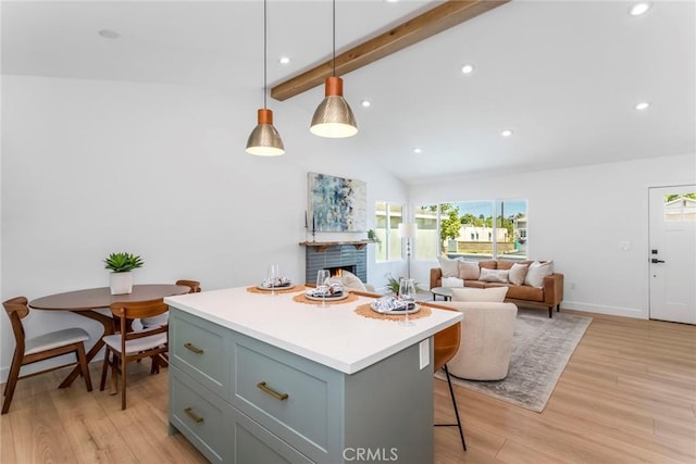 kitchen with light wood-style floors, a kitchen island, light countertops, and beamed ceiling