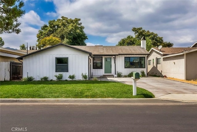 ranch-style home featuring board and batten siding, fence, driveway, and a front lawn