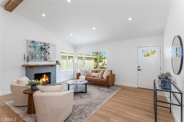 living room featuring light wood finished floors, a warm lit fireplace, baseboards, and recessed lighting