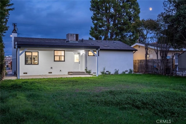 back of property with a yard, crawl space, fence, and stucco siding