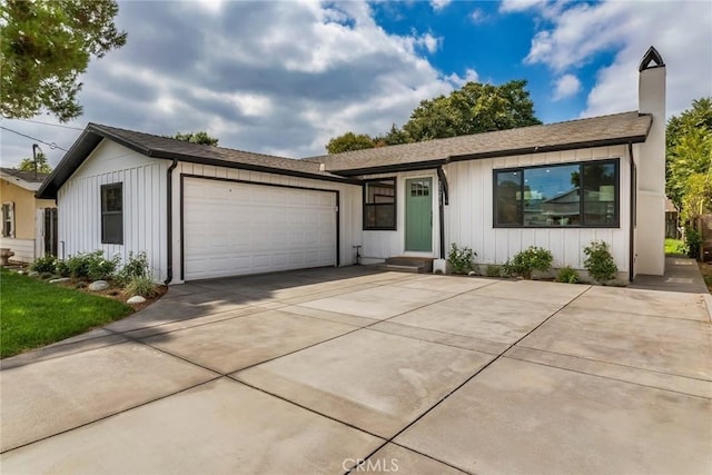 view of front of house featuring a garage, driveway, board and batten siding, and a chimney