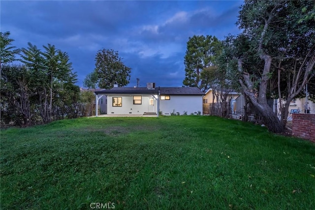 rear view of house featuring a patio area, a fenced backyard, a lawn, and stucco siding