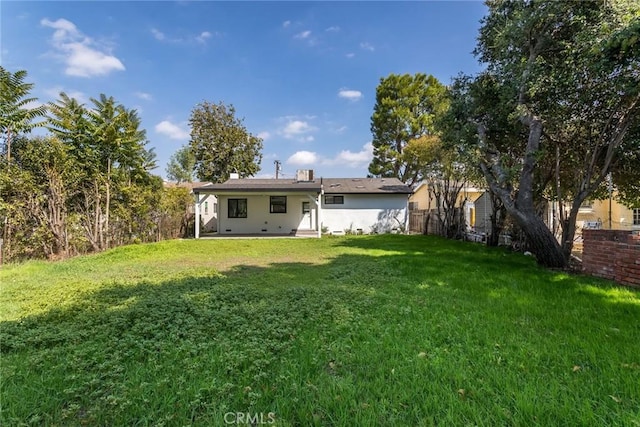 back of property with a lawn, fence, and stucco siding