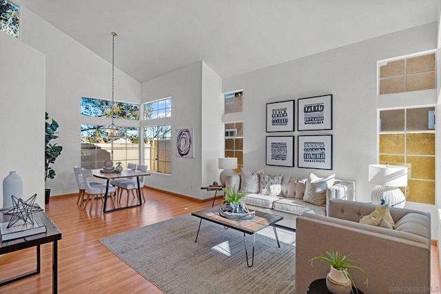 living room featuring high vaulted ceiling, a chandelier, and hardwood / wood-style flooring