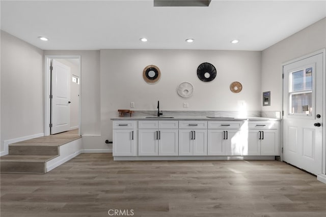 kitchen with a sink, light wood-style flooring, recessed lighting, and white cabinetry