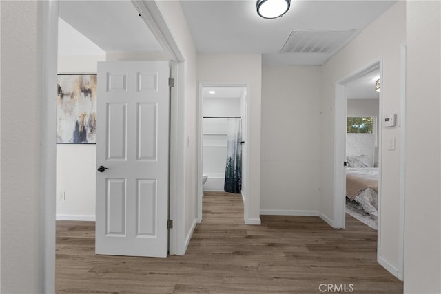 hall featuring baseboards, visible vents, and wood finished floors
