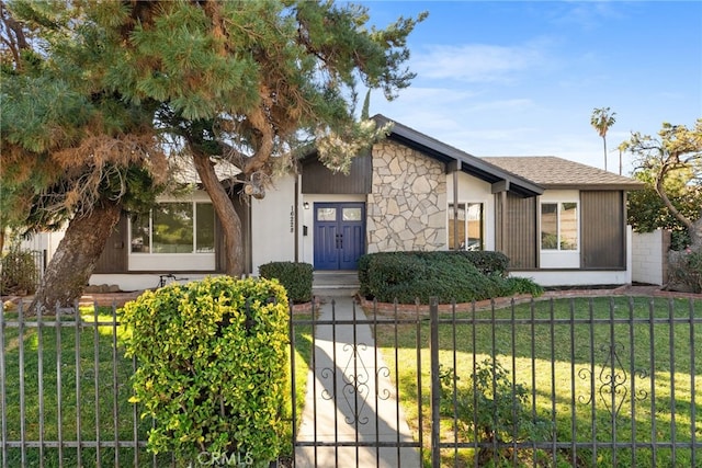 view of front of property with a shingled roof, a fenced front yard, and a front yard