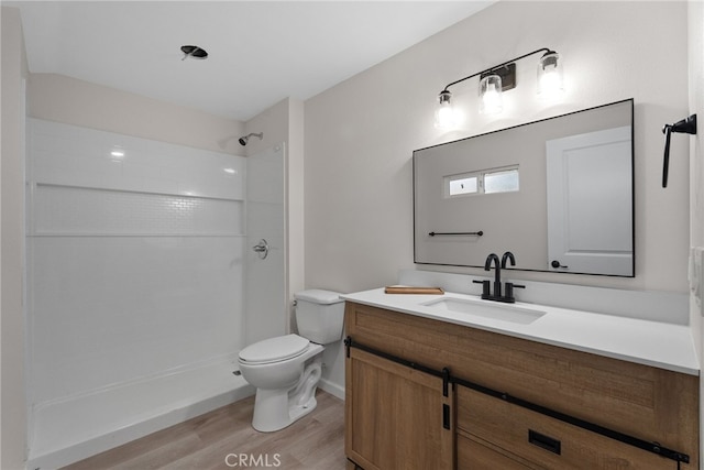 bathroom featuring toilet, walk in shower, wood finished floors, and vanity