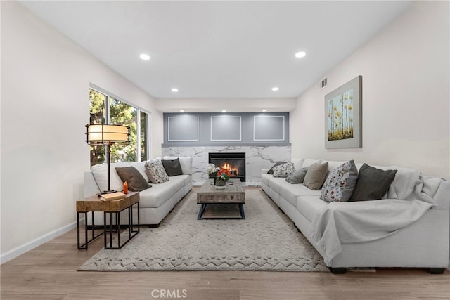 living room featuring visible vents, wood finished floors, a fireplace, baseboards, and recessed lighting