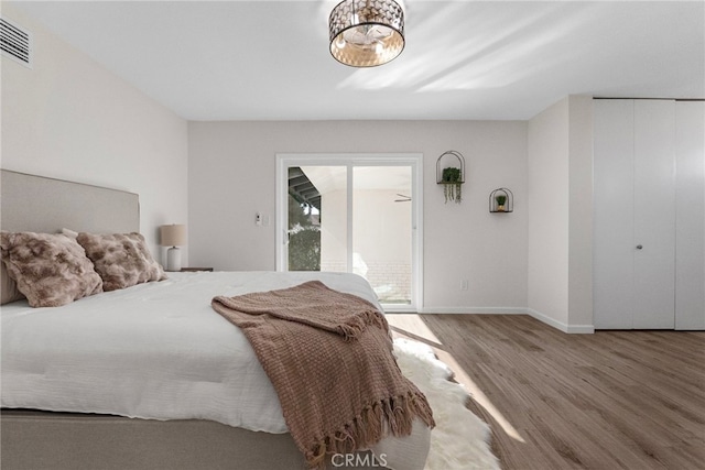 bedroom with baseboards, visible vents, and wood finished floors