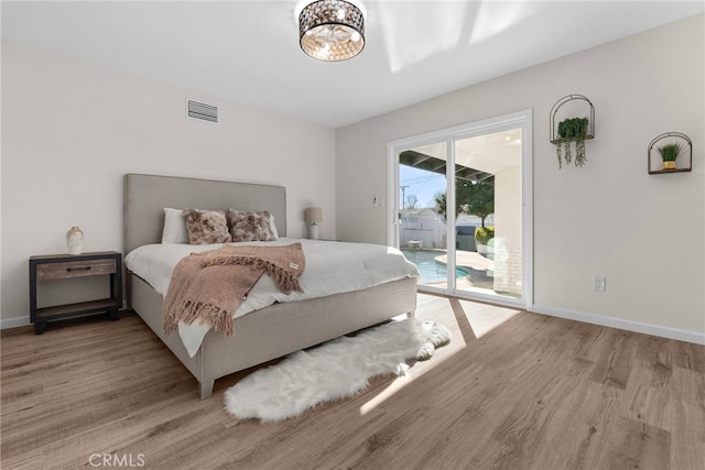 bedroom featuring baseboards, access to outside, wood finished floors, and visible vents