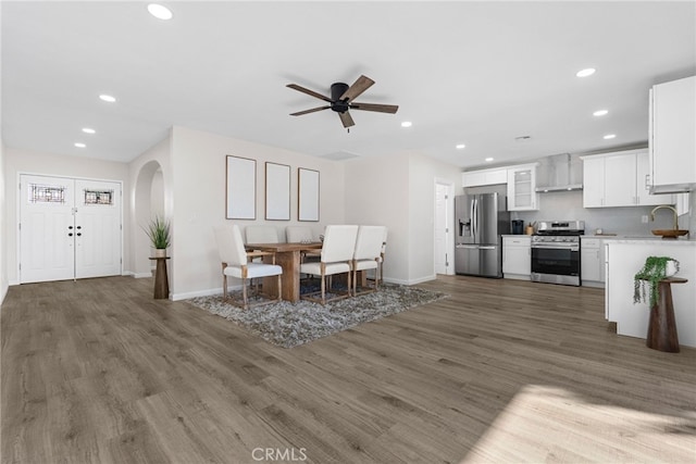 living area featuring recessed lighting, arched walkways, and wood finished floors