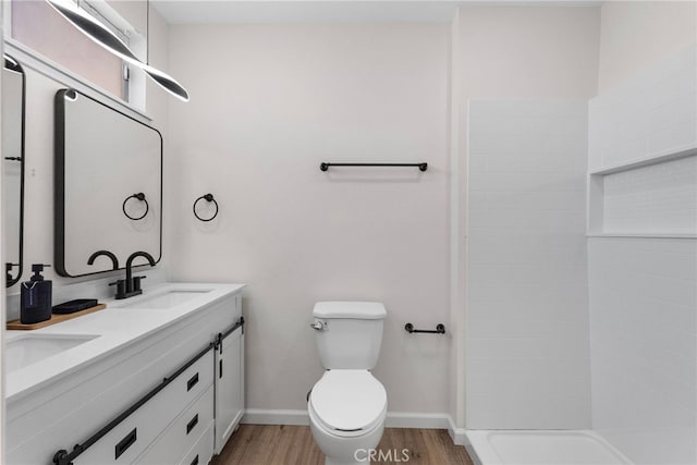 bathroom featuring toilet, baseboards, a sink, and wood finished floors