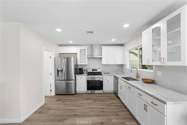 kitchen with visible vents, wall chimney range hood, tasteful backsplash, a sink, and appliances with stainless steel finishes