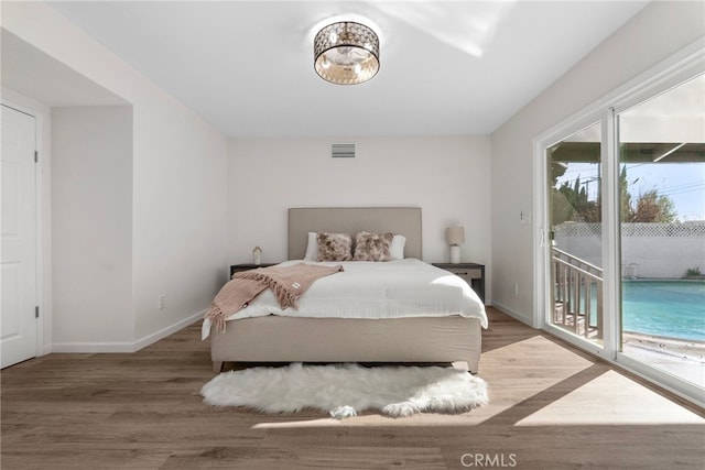 bedroom with visible vents, baseboards, wood finished floors, and access to outside