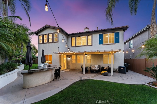 back house at dusk with cooling unit, an outdoor bar, a patio, a lawn, and area for grilling