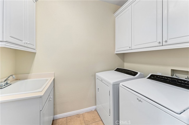 laundry area featuring sink, light tile patterned flooring, cabinets, and separate washer and dryer