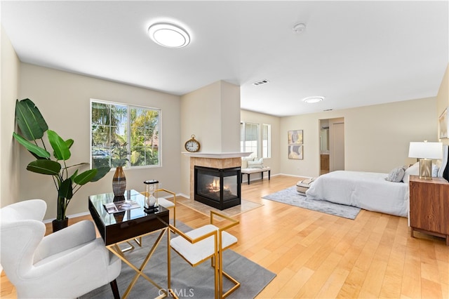 bedroom with light hardwood / wood-style flooring and a tiled fireplace