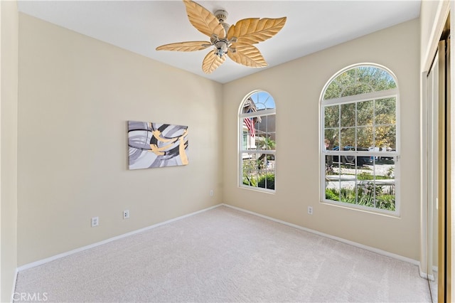 empty room featuring ceiling fan and light carpet