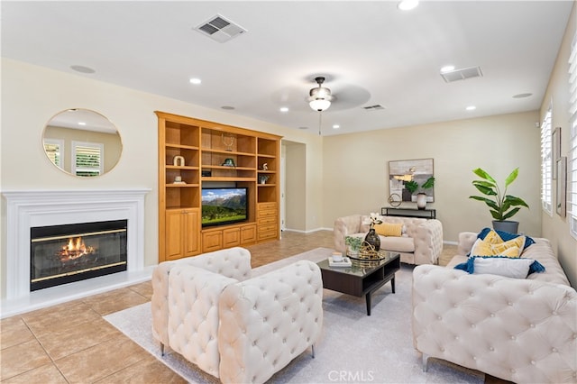 tiled living room with ceiling fan and built in features