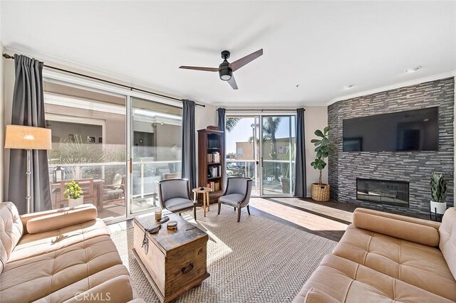 living room featuring ceiling fan, a fireplace, and ornamental molding