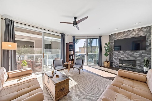 living area with a large fireplace, a ceiling fan, and crown molding