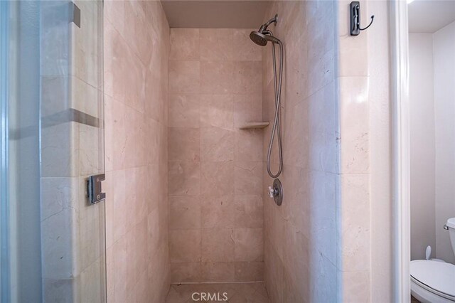 bathroom with toilet and a tile shower