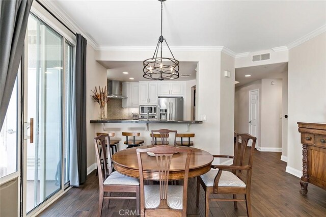 dining space with dark wood-type flooring, plenty of natural light, crown molding, and an inviting chandelier