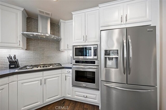 kitchen with tasteful backsplash, wall chimney range hood, stainless steel appliances, and white cabinetry