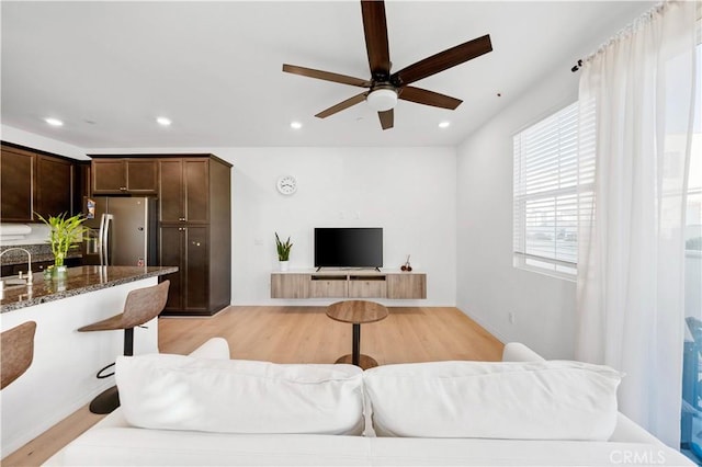 living room with ceiling fan, light wood-type flooring, and sink