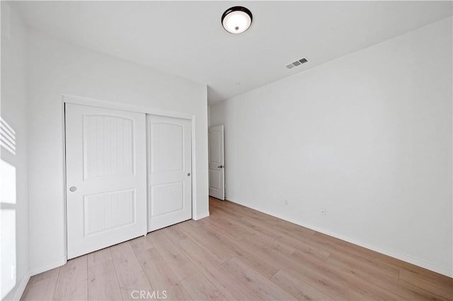 unfurnished bedroom featuring light wood-type flooring and a closet