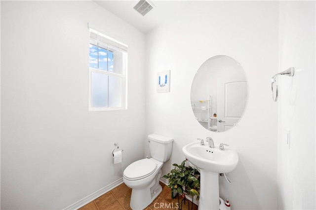 bathroom with toilet, sink, and tile patterned floors