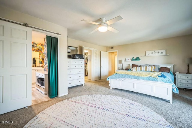 bedroom with ceiling fan, connected bathroom, and light carpet